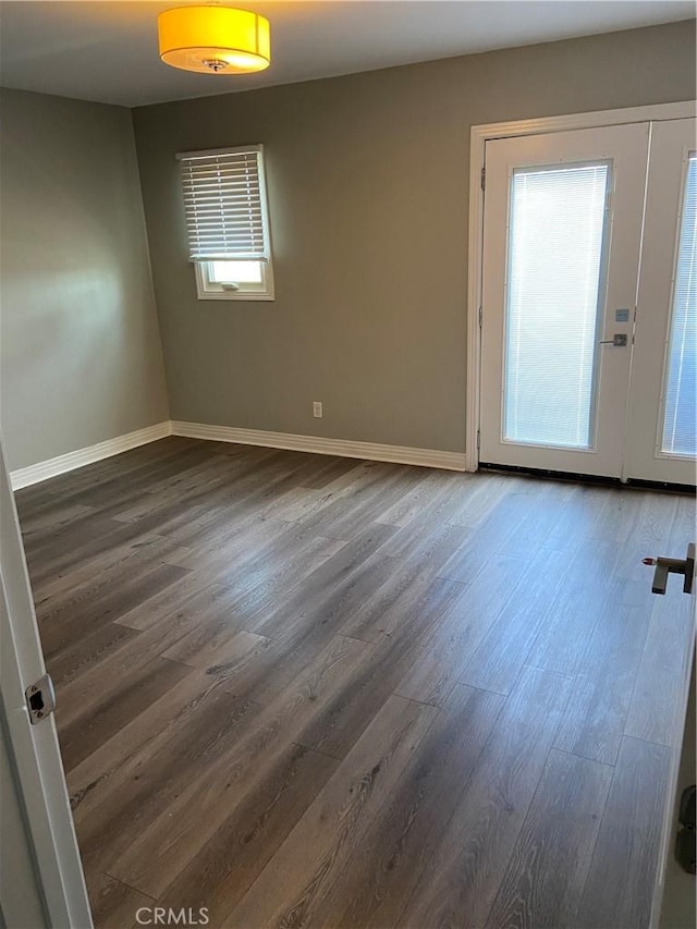 unfurnished room featuring baseboards and dark wood-type flooring