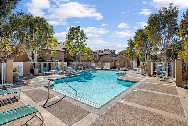 community pool featuring a patio area, a residential view, and fence