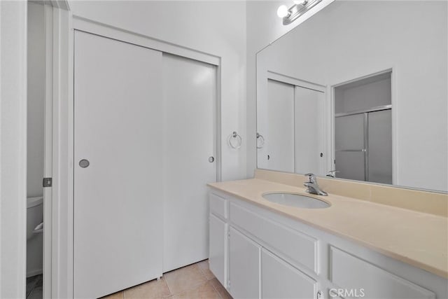 bathroom featuring a shower with door, vanity, and tile patterned floors