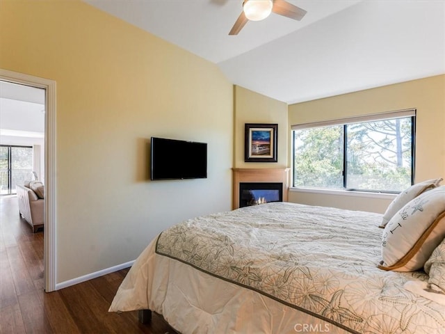 bedroom with multiple windows, baseboards, vaulted ceiling, and wood finished floors