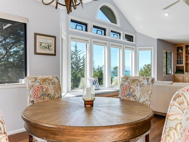 dining area with a notable chandelier, vaulted ceiling, and wood finished floors