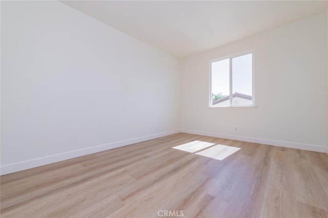 spare room with light wood-type flooring and baseboards