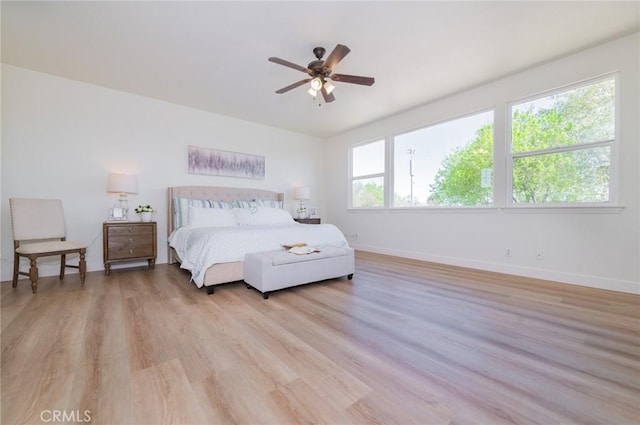 bedroom featuring a ceiling fan, baseboards, and light wood finished floors