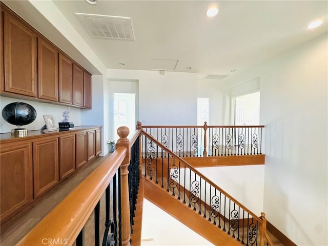 hallway featuring an upstairs landing, visible vents, and recessed lighting