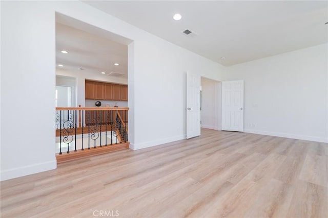 spare room featuring recessed lighting, baseboards, and light wood finished floors