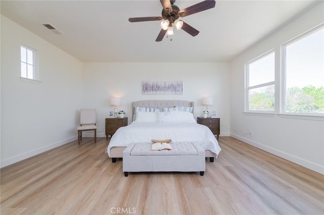 bedroom featuring ceiling fan, visible vents, baseboards, and light wood-style flooring