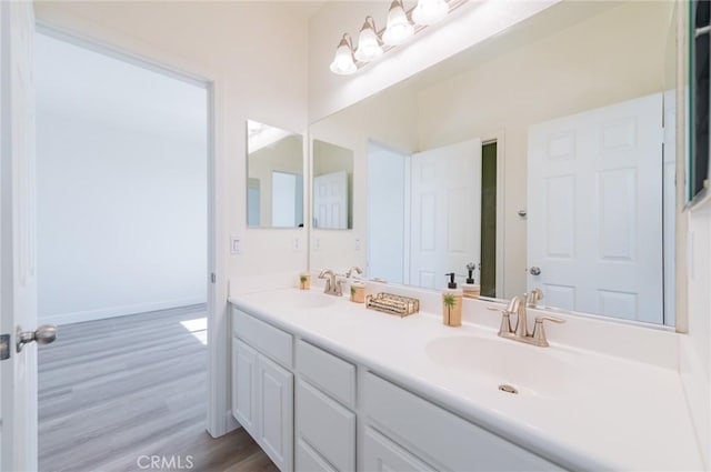 bathroom featuring a sink, baseboards, wood finished floors, and double vanity