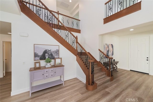 entrance foyer with wood finished floors, baseboards, and a towering ceiling