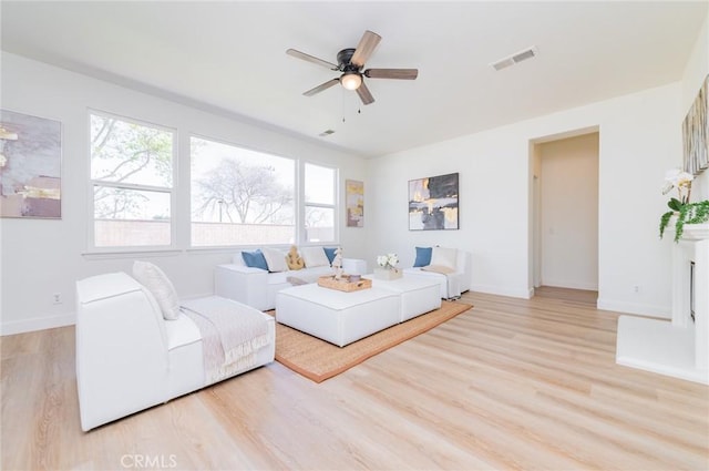 living area with a ceiling fan, baseboards, visible vents, and light wood-type flooring