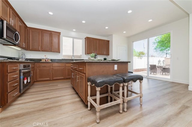 kitchen featuring light wood-style flooring, a healthy amount of sunlight, a kitchen island, and stainless steel appliances