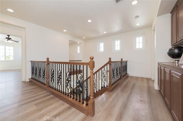 hall featuring a wealth of natural light, an upstairs landing, light wood-style flooring, and baseboards