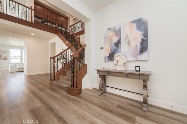 stairs featuring a high ceiling, baseboards, and wood finished floors