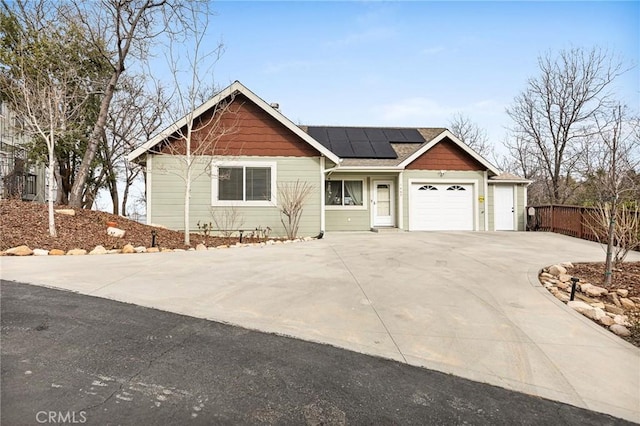 view of front of house with a garage, driveway, roof mounted solar panels, and fence