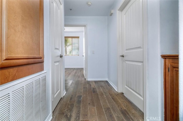 hall with dark wood-style floors, visible vents, and baseboards