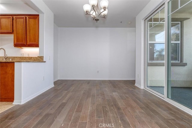 unfurnished dining area with a notable chandelier, baseboards, and dark wood-style flooring