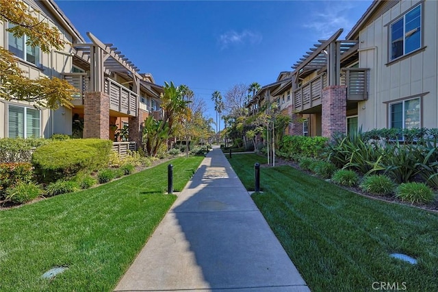 view of property's community with a yard and a pergola