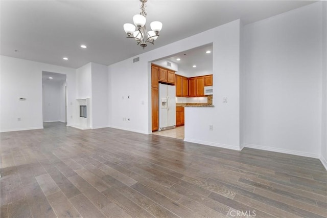 unfurnished living room featuring recessed lighting, visible vents, light wood-style floors, a glass covered fireplace, and an inviting chandelier