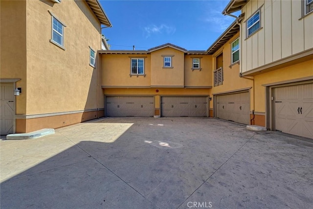 exterior space featuring a garage, driveway, and stucco siding