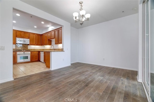 kitchen featuring light wood-type flooring, white appliances, a notable chandelier, and recessed lighting