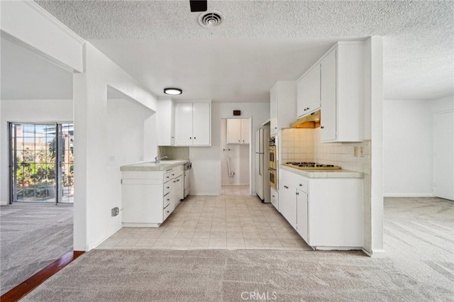 kitchen featuring light countertops, visible vents, backsplash, and light carpet