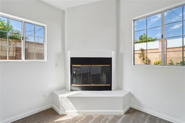 interior details with a glass covered fireplace, carpet, and baseboards