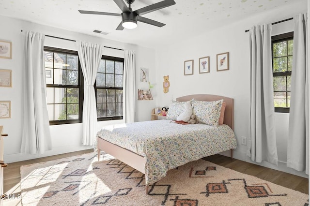 bedroom featuring wood finished floors, visible vents, and a ceiling fan