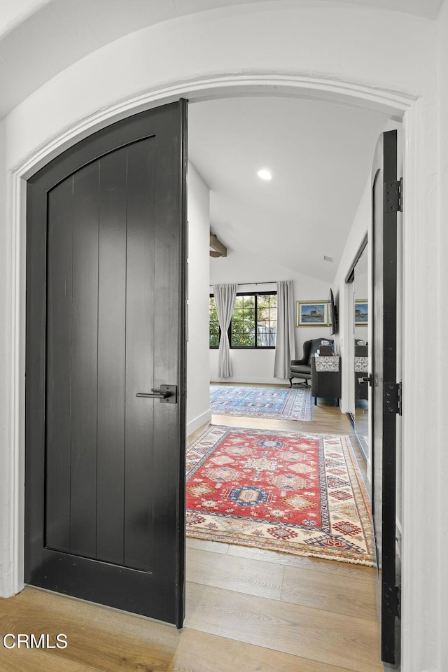 hallway featuring lofted ceiling, wood-type flooring, arched walkways, and recessed lighting