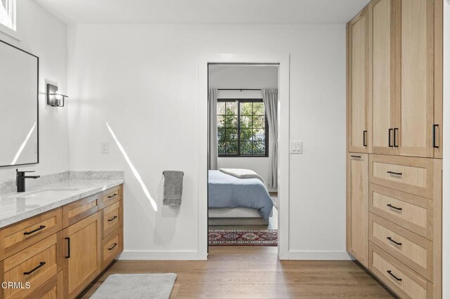 bathroom featuring ensuite bathroom, vanity, baseboards, and wood finished floors