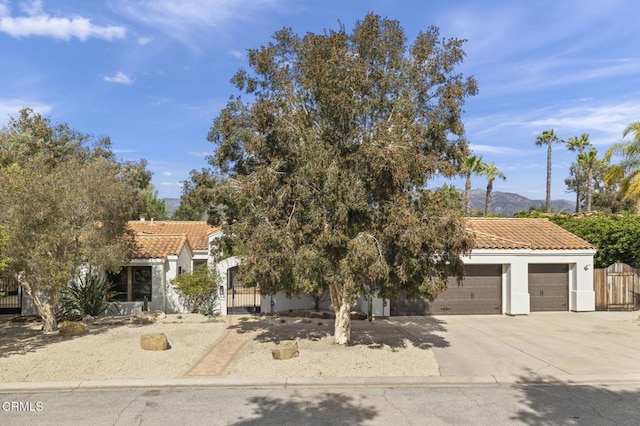 view of front of home with a tiled roof, an attached garage, fence, and driveway