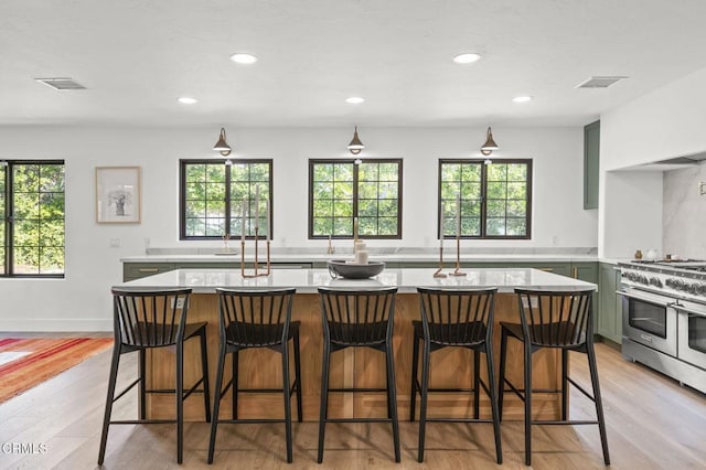 kitchen featuring recessed lighting, visible vents, light wood-type flooring, double oven range, and green cabinetry