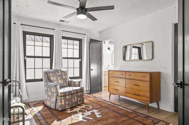 living area with a ceiling fan, visible vents, baseboards, and wood finished floors