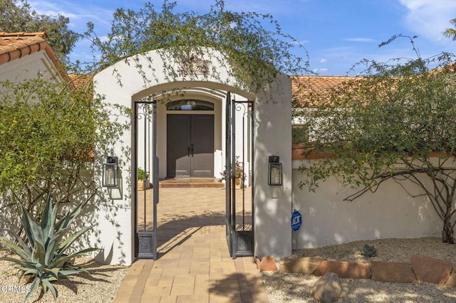 property entrance featuring fence, a gate, and stucco siding