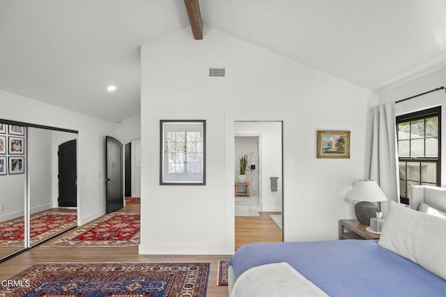 bedroom featuring arched walkways, beam ceiling, visible vents, and wood finished floors