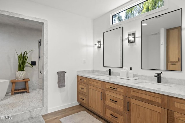 full bath featuring double vanity, walk in shower, a sink, and wood finished floors