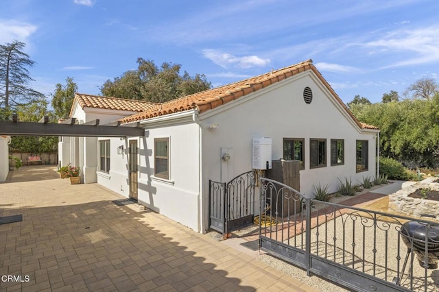 view of front facade featuring a patio area, fence, a tile roof, and stucco siding