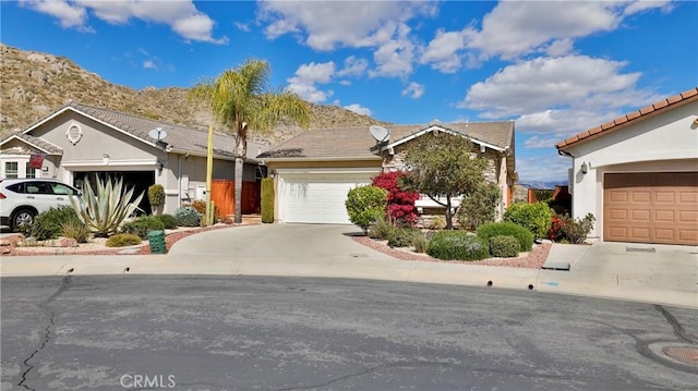 ranch-style house with driveway, an attached garage, and stucco siding