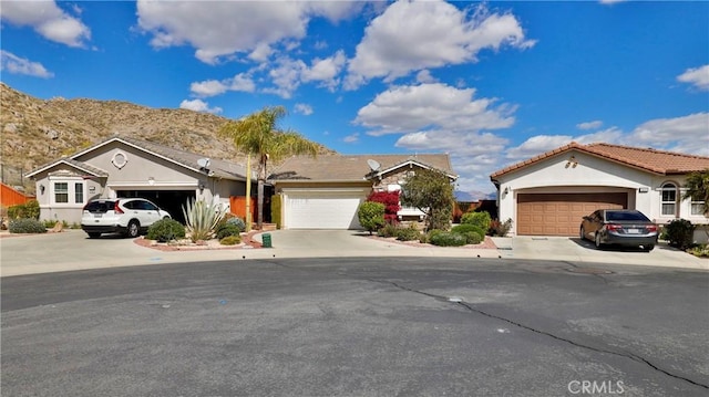 view of front of home featuring an attached garage, a tiled roof, concrete driveway, and stucco siding