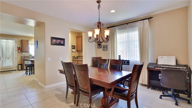 dining space with light tile patterned floors, baseboards, and a notable chandelier