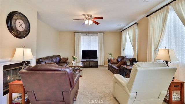 living room with light carpet, ceiling fan, visible vents, and a glass covered fireplace