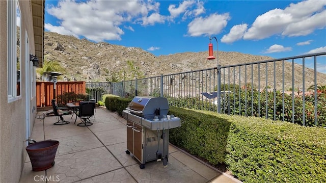 view of patio / terrace featuring outdoor dining space, grilling area, fence, and a mountain view