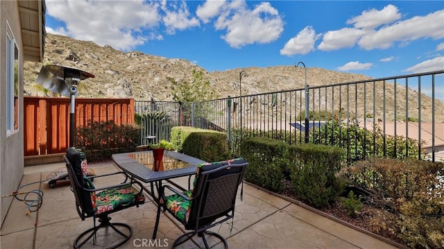 view of patio / terrace featuring outdoor dining area, fence, and a mountain view