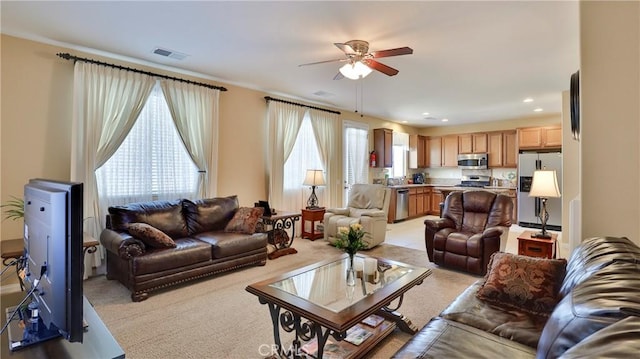 living room featuring light colored carpet, visible vents, and ceiling fan