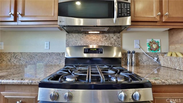 kitchen featuring tasteful backsplash, appliances with stainless steel finishes, brown cabinets, and ventilation hood