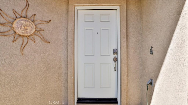 doorway to property featuring stucco siding