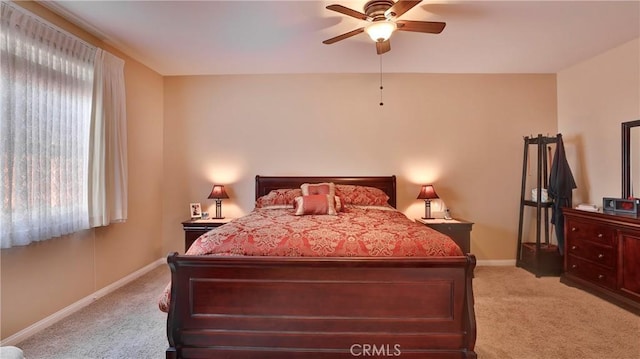 bedroom with baseboards, multiple windows, a ceiling fan, and light colored carpet