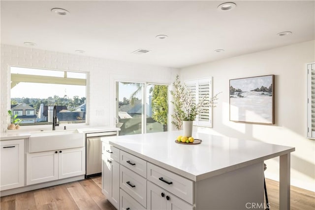 kitchen featuring light wood-type flooring, a sink, recessed lighting, light countertops, and dishwasher