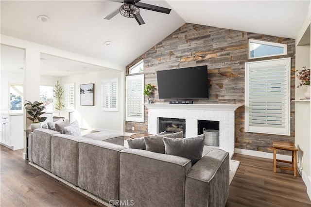 living area with a brick fireplace, baseboards, vaulted ceiling, wood finished floors, and a ceiling fan