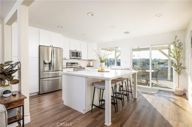 kitchen featuring dark wood finished floors, a kitchen island, white cabinetry, and stainless steel appliances