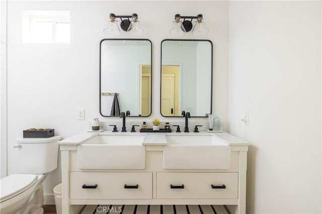 full bath with a sink, toilet, and double vanity