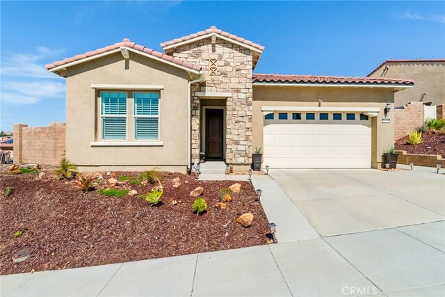 mediterranean / spanish home with a tiled roof, stucco siding, an attached garage, and concrete driveway